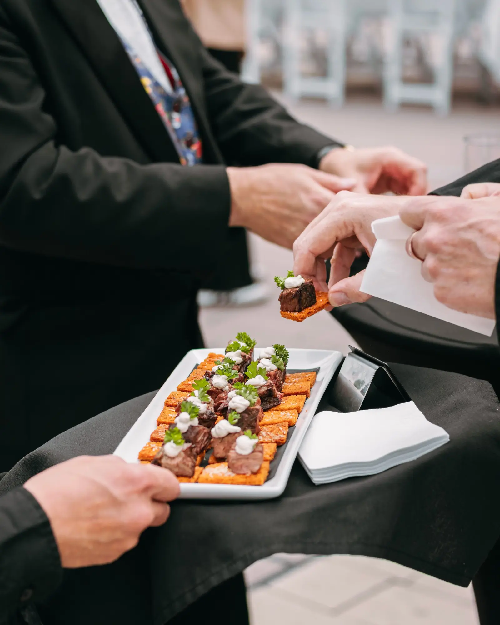 Catering team presenting plated canapes on a service table at an event.